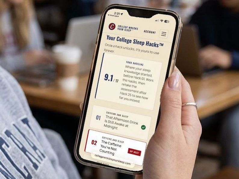 A student holding a phone showing their College Sleep Hacks program, with a baseline assessment score, the first hack marked complete, and the second marked up next.
